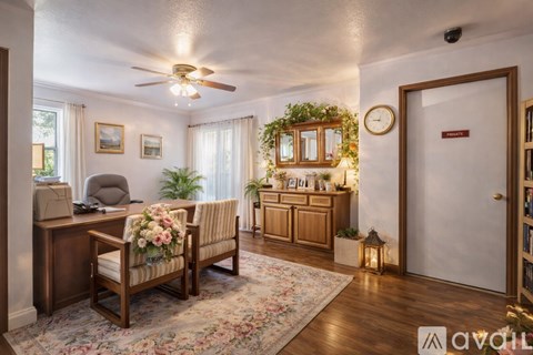 A living room with a sofa, chair, and a table with a vase of flowers on it.