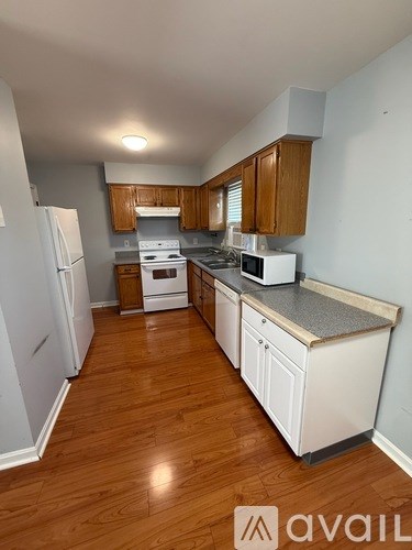 A kitchen with wooden floors and white appliances.