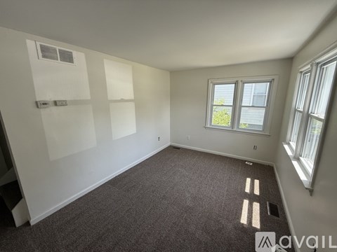 A room with a carpeted floor, a window, and a wall-mounted shelf.