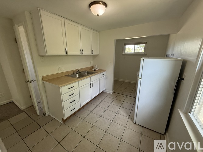 A kitchen with white cabinets and a white refrigerator.