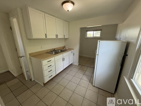 A kitchen with white cabinets and a white refrigerator.