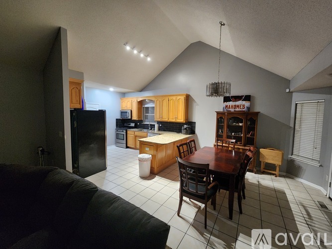 A kitchen with a refrigerator, microwave, and a dining table with chairs.