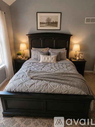 A bedroom with a large bed and a picture on the wall.
