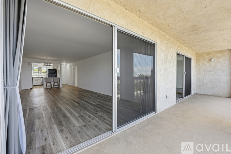 A spacious room with wooden flooring and sliding glass doors.