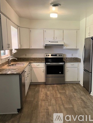 A kitchen with white cabinets and a granite countertop.