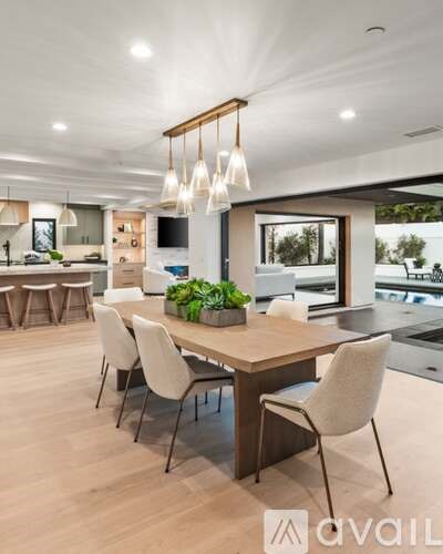 A modern dining room with a wooden table and white chairs.