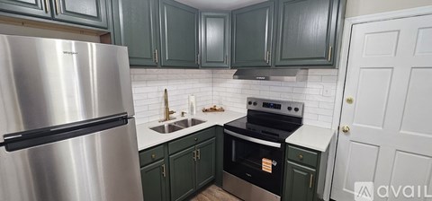 A kitchen with green cabinets and a stainless steel refrigerator.