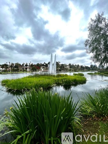 A fountain in the middle of a grassy area with a cloudy sky above.