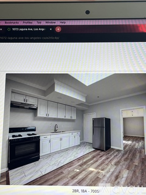 A kitchen with white cabinets and a black refrigerator.