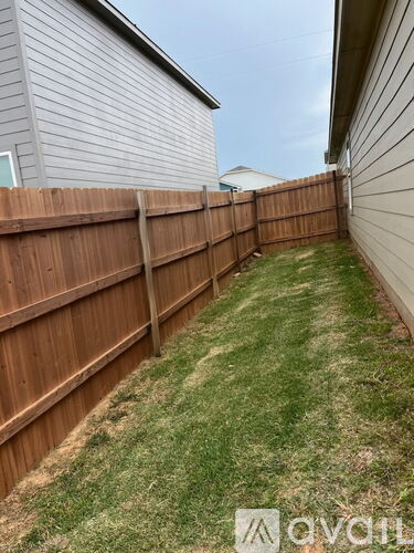 A backyard with a wooden fence and a grassy area.