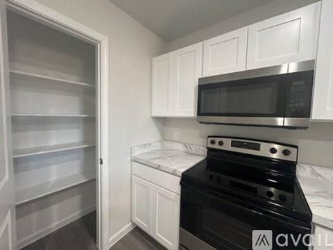 A kitchen with a black stove top oven and white cabinets.