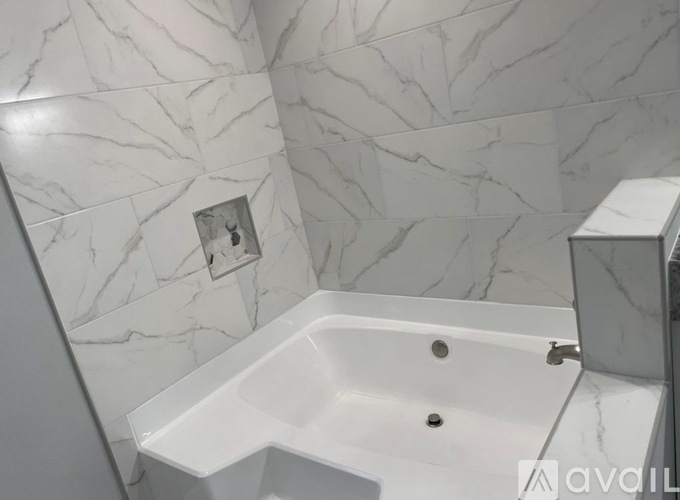 A white bathroom with a marble tile wall and a white bathtub.