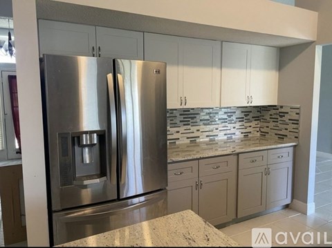 A modern kitchen with a stainless steel refrigerator and white cabinets.