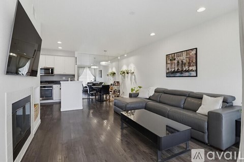 A modern living room with a grey sofa and a television on the wall.