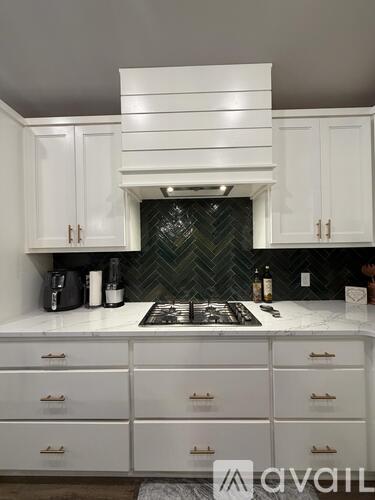 A kitchen with white cabinets and a black backsplash.