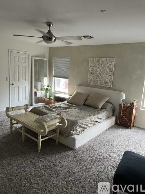 A bedroom with a bed, a bench, and a ceiling fan.