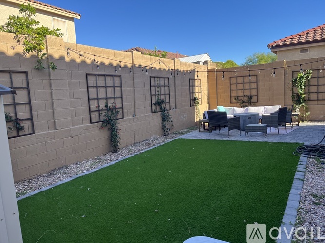 A backyard with a table and chairs set up on a green lawn.