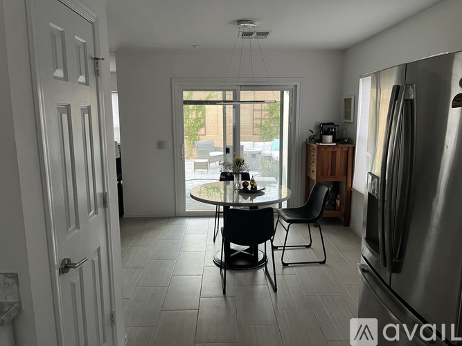 A kitchen with a table and chairs in front of a sliding glass door.