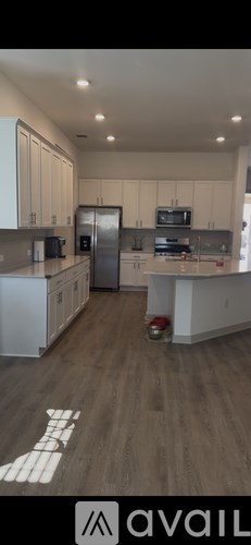 A kitchen with white cabinets and a wooden floor.