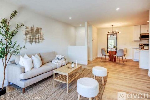 A living room with a couch, a coffee table, and a dining area in the background.