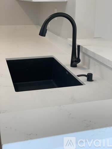 A black kitchen sink with a black faucet on a white countertop.