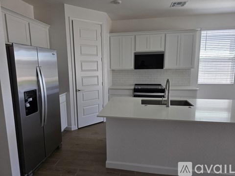A modern kitchen with white cabinets and a stainless steel refrigerator.