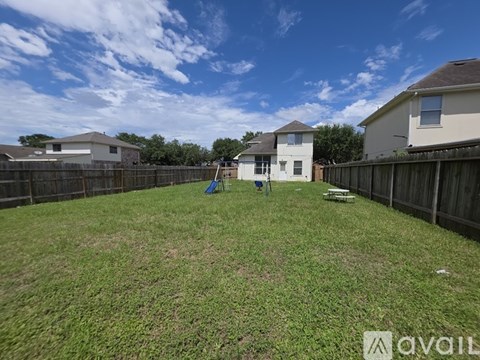 A backyard with a wooden fence and a white house in the background.