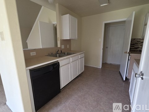 A kitchen with white cabinets and a black dishwasher.