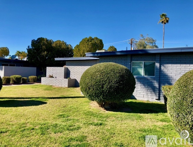 A house with a well-manicured lawn and a palm tree in the background.