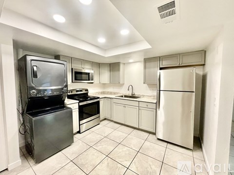 A kitchen with white cabinets and a stainless steel refrigerator.