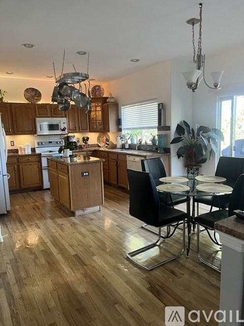 A kitchen with wooden floors and a dining table with chairs.