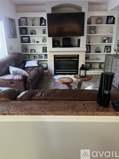 A living room with a brown leather couch and a fireplace.