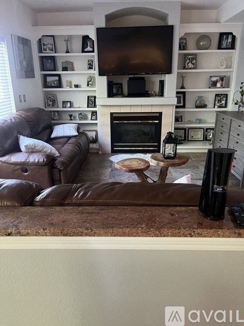 A living room with a brown leather couch and a fireplace.