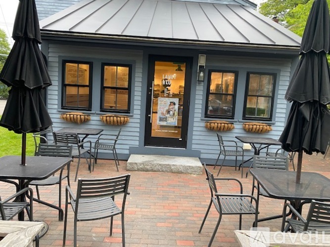 A small blue building with a black umbrella in front.