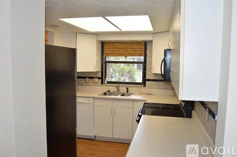 A kitchen with white cabinets and a black refrigerator.