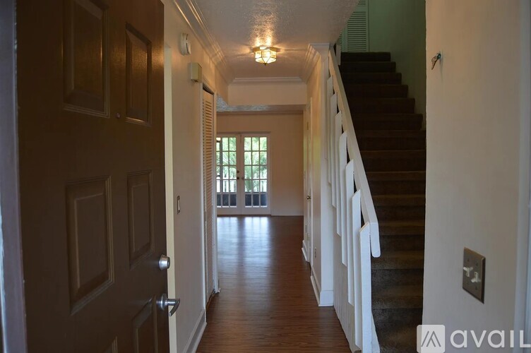 A hallway with a staircase on the right and a door on the left.