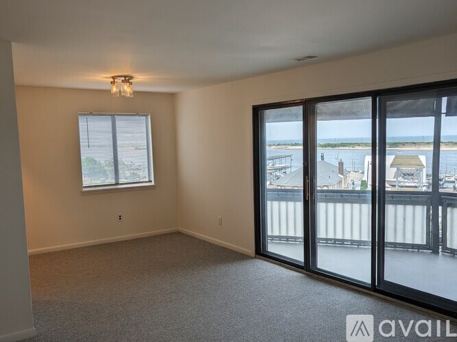 A room with a large window and sliding glass doors leading to a balcony.