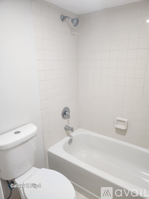 A white toilet sits next to a white bathtub in a bathroom.