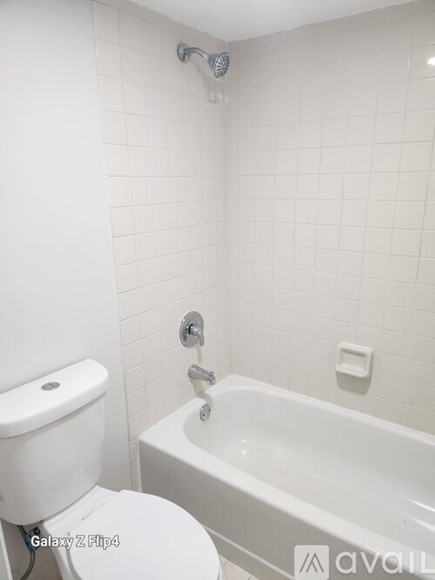 A white toilet sits next to a white bathtub in a bathroom.
