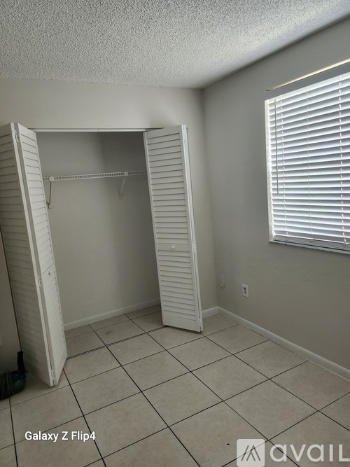 A room with a closet and a window with blinds.