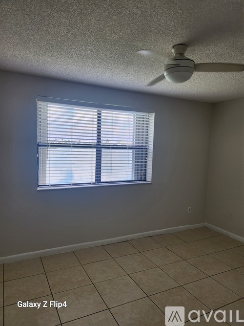 A room with a ceiling fan and a window with blinds.