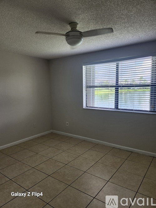 A room with a ceiling fan and a window with blinds.