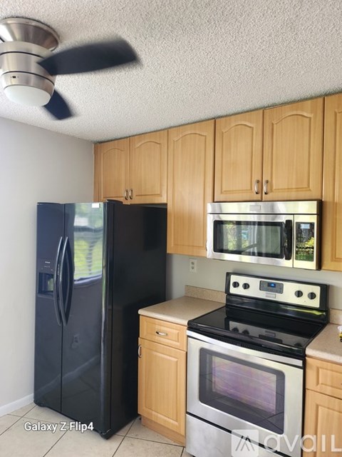A kitchen with a black fridge, stove, and wooden cabinets.