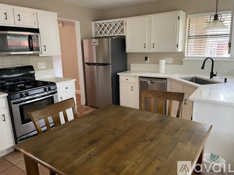 A kitchen with a wooden table and white cabinets.