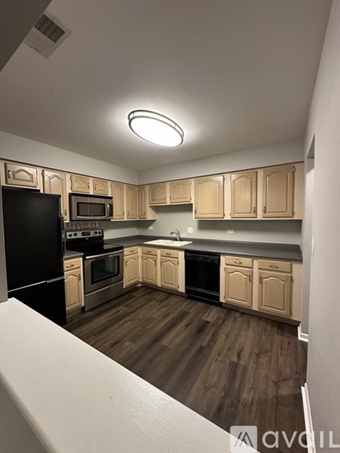 A kitchen with wooden cabinets and black appliances.