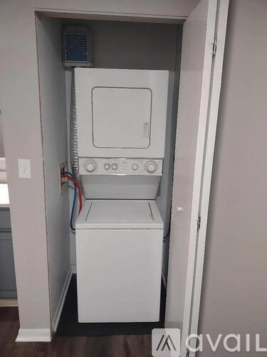 A white dishwasher is installed in a narrow space between a wall and a door.