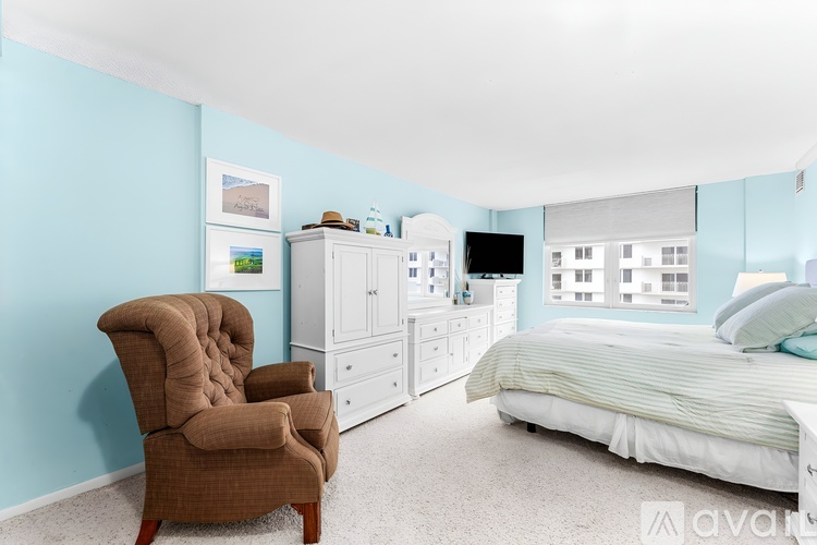 A brown chair is in a bedroom with a bed and a dresser.