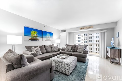 A living room with a grey sofa and a coffee table in front of a large window.