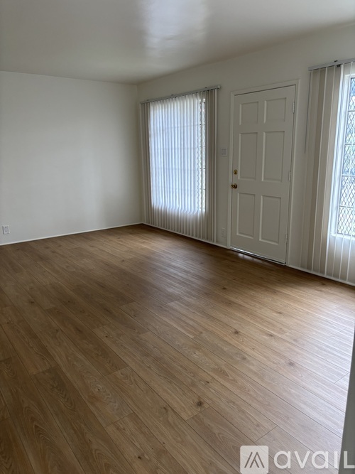 A room with wooden flooring and a white door.