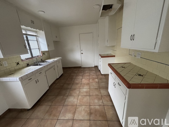 A kitchen with white cabinets and a tiled floor.